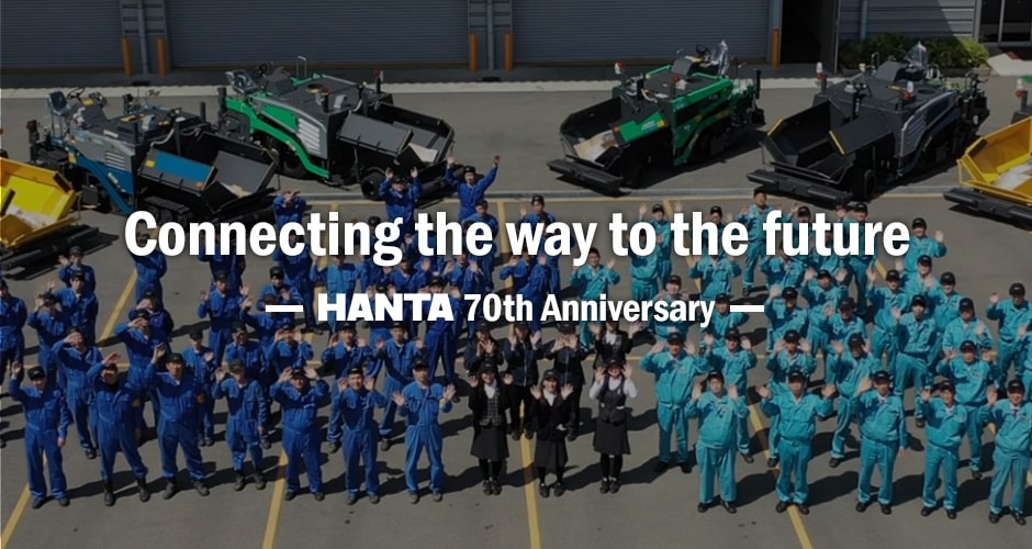 HANTA 70th Anniversary - Connecting the way to the future. Employees celebrating with asphalt finishers in the background.